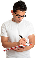 Image showing Student in glasses writes in book