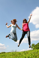 Image showing two girls jump under blue sky