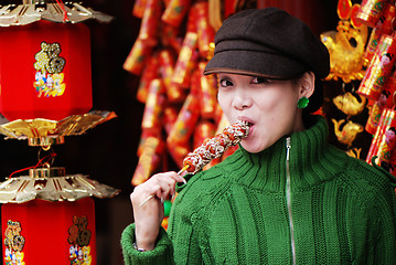 Image showing China girl eating candied fruit