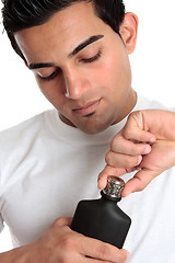 Image showing Guy removes lid from aftershave bottle