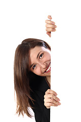 Image showing Cheerful woman looks out from behind an unmarked plate. 