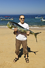 Image showing Tourist holding big fish on beach