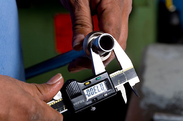 Image showing Hands Holding a Tool Measuring a Pipe