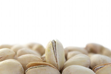 Image showing Single standing pistachio among lying ones