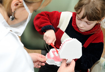 Image showing A little girl learning to clean a teeth at a dentist