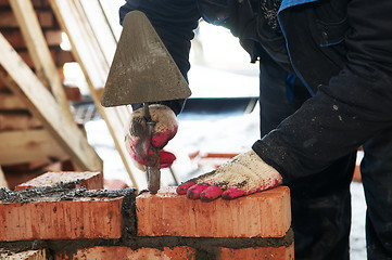 Image showing hands of a mason at bricklaying work