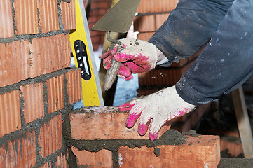 Image showing hands of a mason at bricklaying work