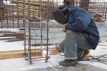 Image showing worker welding a metal lattice at construction site