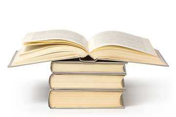 Image showing A pile of books, top one is open