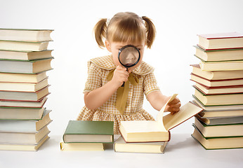 Image showing Little girl looking at book through magnifier