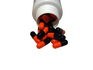 Image showing Multicolored capsules out of the bottle on white