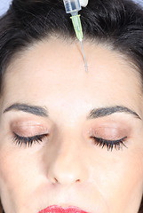 Image showing Young woman receives botox injection in her forehead