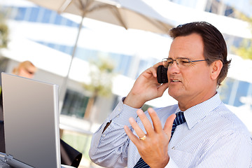 Image showing Businessman Talking on Cell Phone Using Laptop