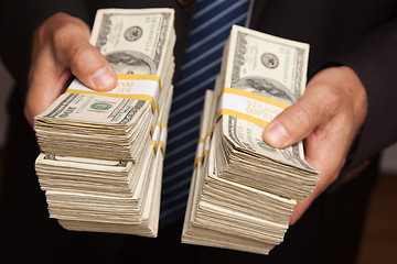 Image showing Businessman Handing Over Stacks of Money