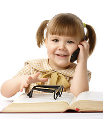 Image showing Happy little girl with book and a cell phone