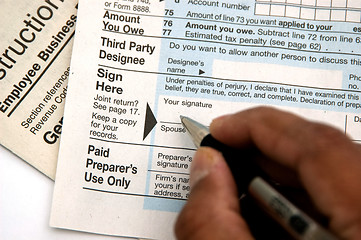 Image showing Hand signing a tax form concept of filing tax