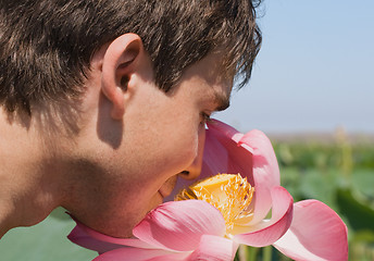 Image showing Young man smelling a pink lotus