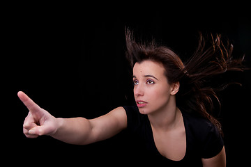 Image showing beautiful young woman with her hair in the wind, finger in the air, looking up