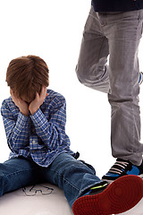 Image showing child crying on the floor being kicked by a teenager