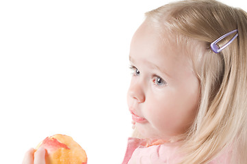 Image showing Little girl eating peach in studio