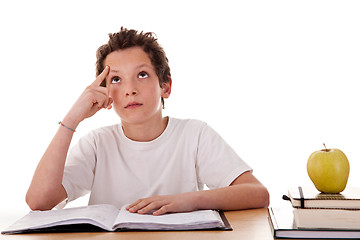 Image showing boy studying and thinking, along with one on apple top of some books