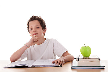 Image showing boy studying and thinking, along with one on apple top of some books