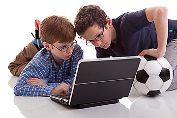 Image showing two boys sitting on the floor playing computer, one holding a football