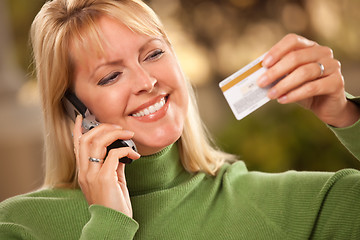 Image showing Cheerful Woman Using Her Phone with Credit Card