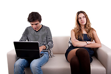 Image showing couple sitting on the couch, he playing computer and she look to other way bored