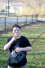 Image showing Young boy eating banana outside