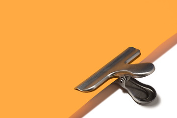 Image showing Metallic paperclip on orange paper