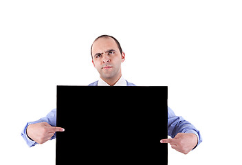 Image showing young business man holding a blackboard and pointing with both hands, looking bored