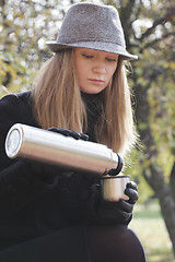 Image showing Woman in black coat filling cup