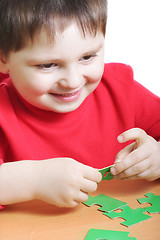 Image showing Smiling kid assembling green puzzles