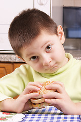 Image showing Grimacing boy with hamburger