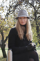 Image showing Woman in black coat and hat with cup