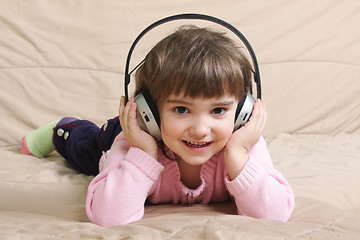 Image showing Smiling girl with headphones on sofa