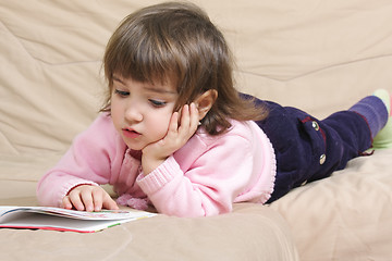 Image showing Little girl reading on sofa