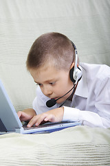 Image showing Serious boy in headset working on laptop