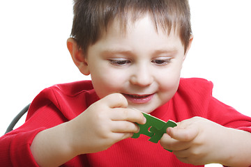 Image showing Smiling boy assembling green puzzles