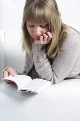 Image showing Woman reading book laying on sofa