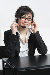 Image showing Businesswoman with headset sitting at desk