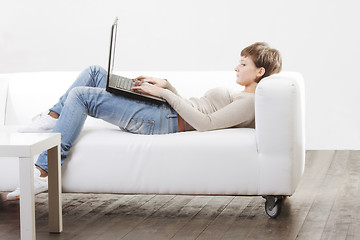 Image showing Young woman on white sofa with computer