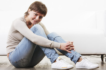 Image showing Smiling woman sitting on floor sideview