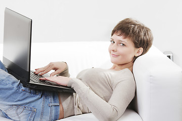 Image showing Young woman on sofa with computer
