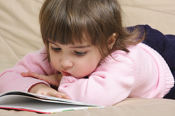 Image showing Little girl reading book on sofa