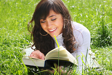 Image showing Smiling brunette reading book on grass