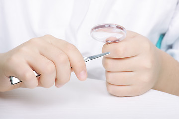 Image showing Researchers hands with magnifier and tweezers