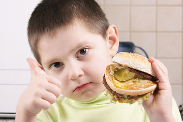 Image showing Serious boy with hamburger