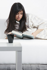 Image showing Brunette woman reading on sofa